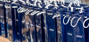 Auf einer Bierzeltgarnitur stehen viele Weintüten in blau mit der Aufschrift "Ehewein".