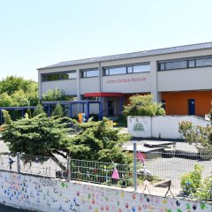 Blick auf den Schulhof ohne Kinder und das weiss rote Schulgebäude der John-Sutton-Grundschule Kiedrich 