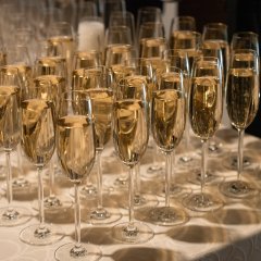 Auf einer beigen Tischdecke stehen mit Sekt gefüllte und ungefüllte Sektgläser.