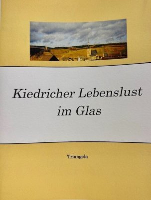 Auf einem gelben Hintergrund ist ein Bild mit der gelben, evangelischen Kirche von Erbach und im Hintergrund die Weinberge und die Burgruine Scharfenstein und ein Himmel mit Wolken. Auf einer weißen Banderole steht in schwarzen Buchstaben der Titel "Kiedricher Lebenslust im Glas".