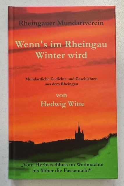 Auf dem Buch sind unten die Farben grün, darüber in schwarz die Umrisse von Baumkronen und eines hohen Gebäudes mit drei Türmen und darüber ein rot-orange-farbener Himmel dargestellt.