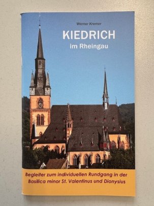 Blauer Himmel ohne Wolken und die Basilica minor mit der St. Michaelskapelle in beige und weinrot und dunkel gedecktem Dach und Kirchtürmen.