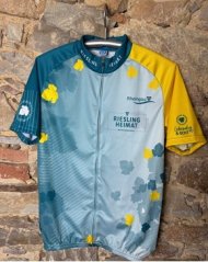 Vorderseite des Radtrikot, mit der Aufschrift Rieslingheimat und dem Rheingau-Logo. Der linke Ärmel ist gelb, der rechte Ärmel petrol. Zur Mitte hin, bei dem ein Reisverschluss ist, wird die Farbe blau heller. Außen sind gelbe und blaue Weinblätter abgebildet. Der Stehkragen ist petrol mit weißen Buchstaben.