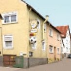 Gelbes Haus mit Werbeschild und Fussball in Reihe vor einem lachsfarbenen und weißem Haus.