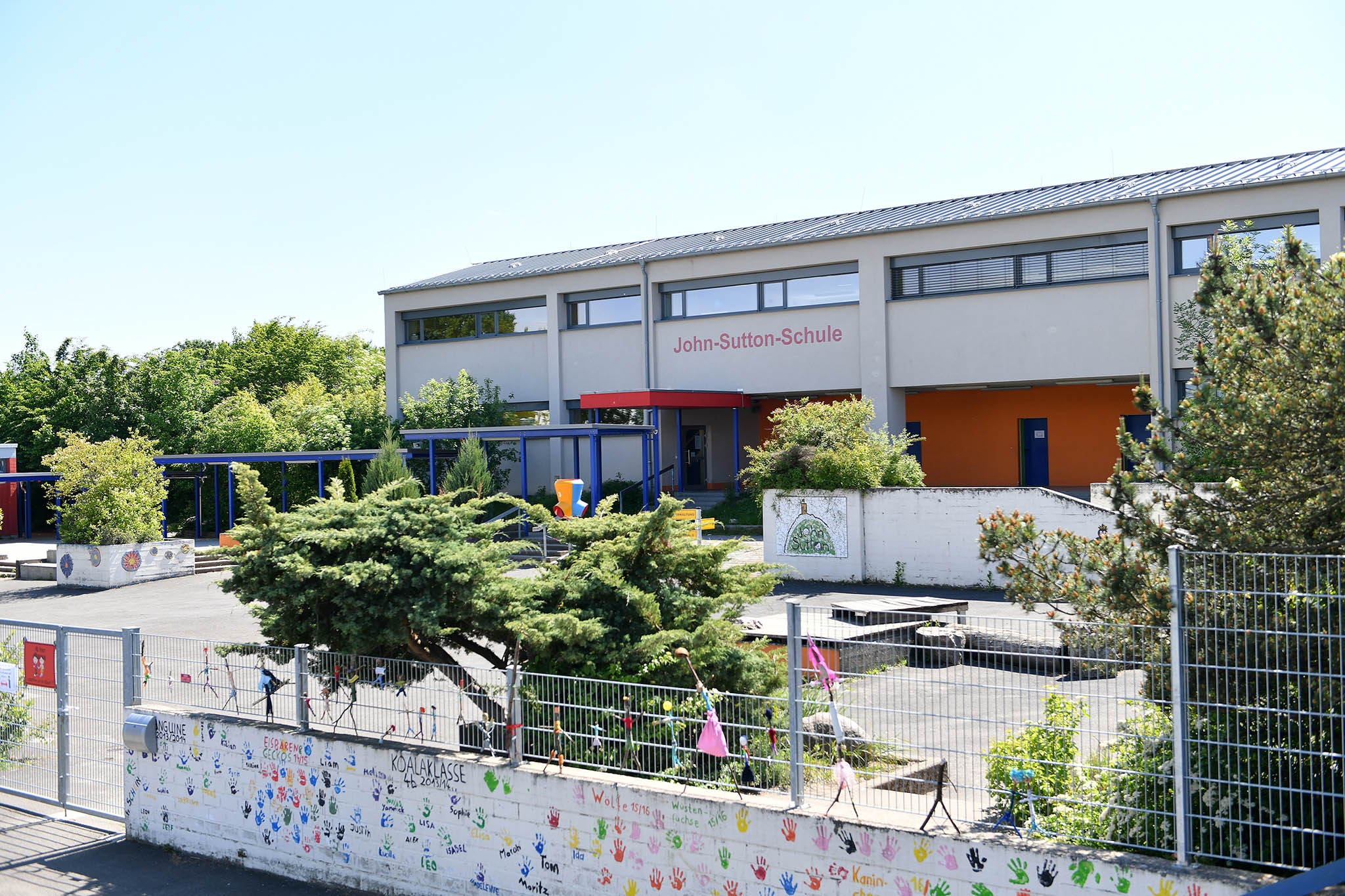 Blick auf den Schulhof ohne Kinder und das weiss rote Schulgebäude der John-Sutton-Grundschule Kiedrich 