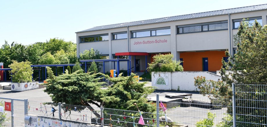 Blick auf den Schulhof ohne Kinder und das weiss rote Schulgebäude der John-Sutton-Grundschule Kiedrich 
