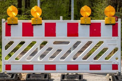 Warnbake Eine Warnbake mit rot-weißen Streifen, aufgestellt auf vier grauen Ständern mit vier gelben Warnleuchten oberhalb des Schrankenzaunes.