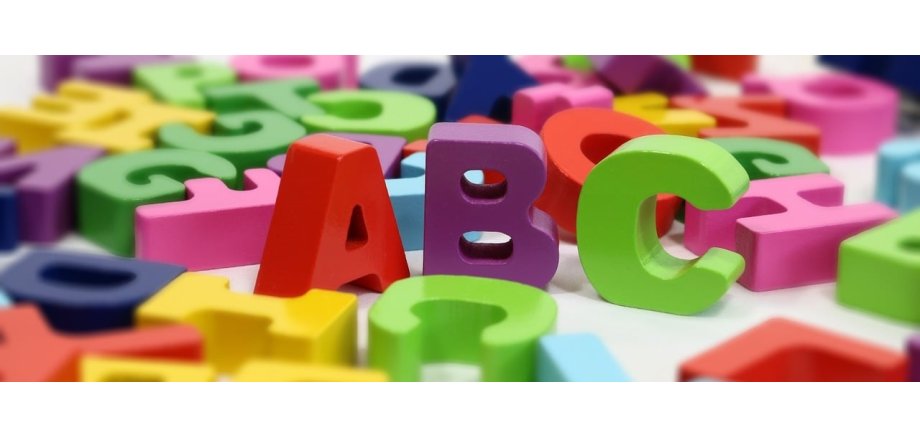 Es stehen aufgestellt drei Buchstaben- ein rotes A, ein lilanes B und ein grünes C. Drum herum liegen weitere Buchstaben in den Farben gelb, lila, blau, hellblau, pink und grün.