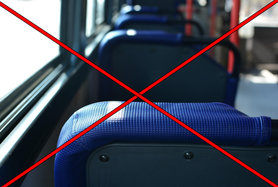 Man sieht verschwommen einen Ausschnitt des Inneren eines Linienbusses, d.h. vier Sitze mit blauem Stoff und grauer Rückseite und rote Haltestangen. Links ist eine breite Fensterreihe zu erkennen. Über dem Bild sind zwei rote Linien, die sich kreuzen.