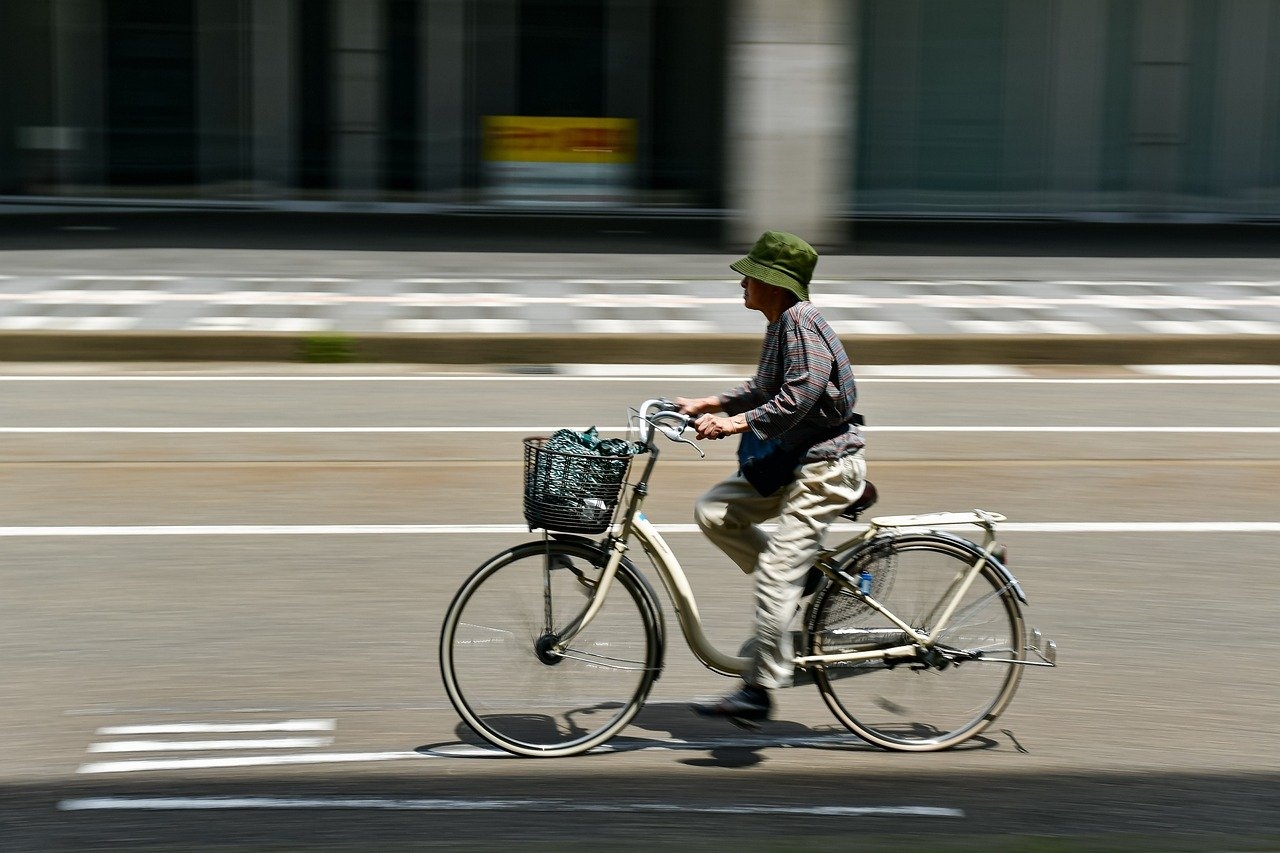 Auf einer autofreien Straße fährt ein Mann mit Hut auf einem Fahrrad.