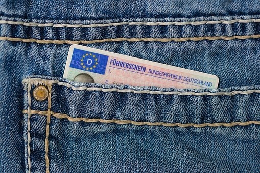 In einer Jeans-Hosentasche steckt die  blau-rosa-beige Führerscheinkarte der BRD