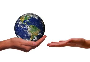 Auf einer flachen Hand liegt die Weltkugel auf der Innenseite der Hand. Eine andere Hand ist geöffnet und bereit, diese entgegenzunehmen. Der Hintergrund ist weiß. 