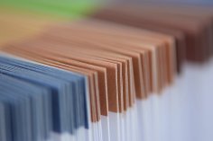 Papiermappen Mehrere Papiermappen werden verschwommen hintereinander gezeigt. Die Ränder oben haben einen Streifen . Die Mappen links haben einen blauen, die mittleren einen hellbraunen und die hinteren Mappen haben einen dunkelbraunen Rand. Unterhalb des Randes sind alle Mappen weiß.