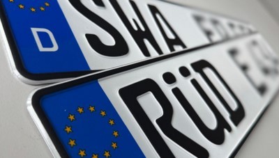 Zwei deutsche KFZ-Kennzeichen mit der Europa-Flagge liegen schräg aufeinander. Das eine Kennzeichen hat die Buchstaben SWA und das andere RÜD und E.