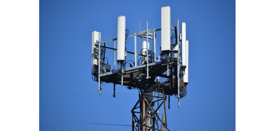 Vor einem blauen Himmel ohne Wolken sieht man einen Mobilfunkmast.