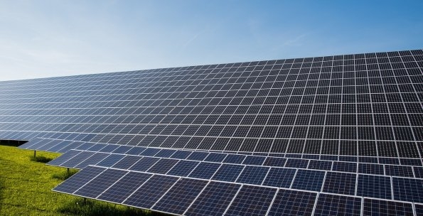Ein Feld von Solarpanel steht auf einer Wiese.