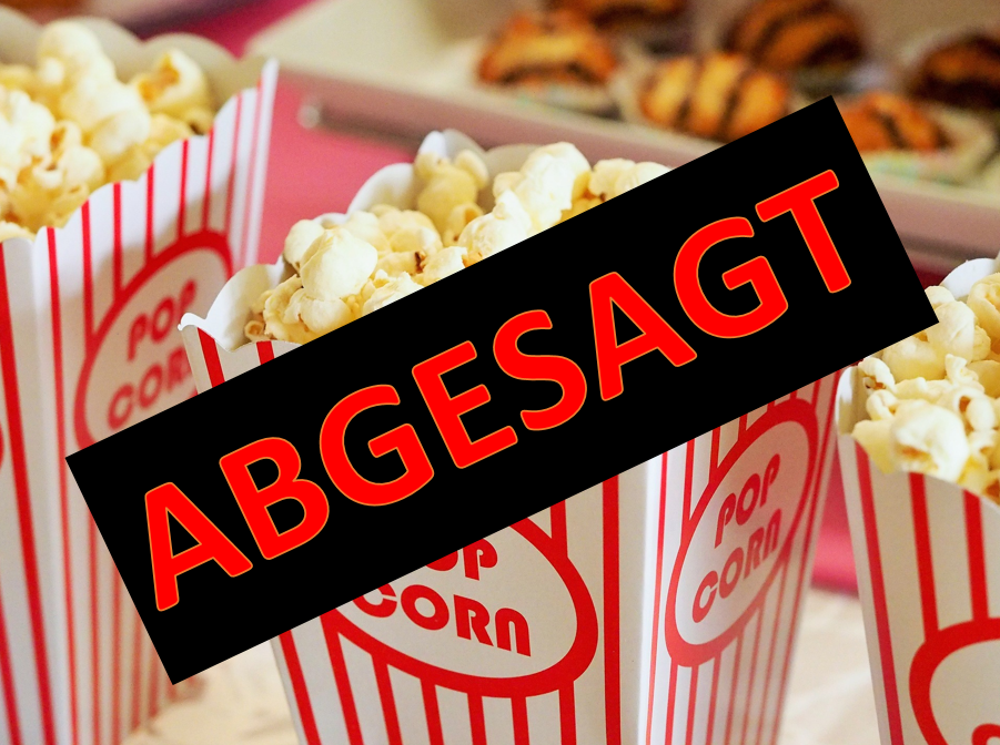 Drei mit Popcorn gefüllte Papierbecher mit weißen und roten Streifen und der roten Aufschrift "Popcorn" stehen vor einem Tablett mit runden Plätzchen  mit Schokoladenstreifen auf weißen Papierförmchen. Der Hintergrund mit den Plätzchenist verschwommen. Über dem Text ist ein schwarzes Rechteck, in dem mit roten Buchstaben "ABGESGT" steht.