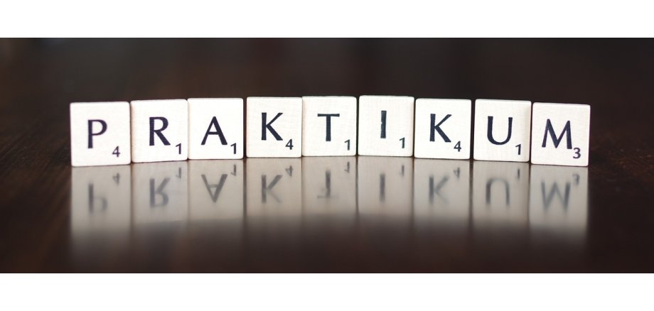Auf einem schwarzen Hintergrund stehen 9 quadratische weiße Steine, auf denen jeweils ein Buchstabe und eine Zahl von 1-4 in schwarzer Schrift aufgezeichnet ist. Die Buchstaben ergeben das Wort "Praktikum".