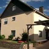 Beiges Haus mit Büschen und braunem Holz-Carport