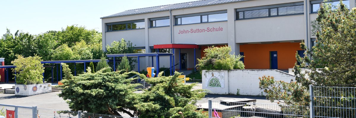 Blick auf den Schulhof ohne Kinder und das weiss rote Schulgebäude der John-Sutton-Grundschule Kiedrich 