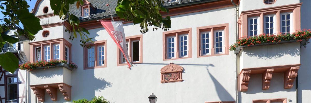 Kiedricher Rathaus, weisses Gebäude mit Sandsteinfensterrahmen und Fahne mit Kiedricher Wappen in rot und weiss