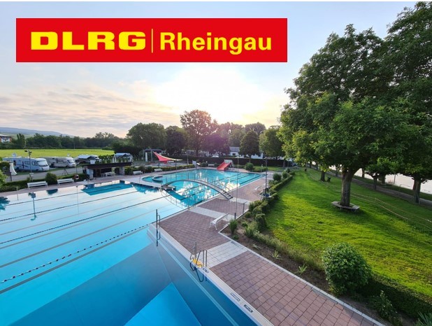 Logo DLRG Rheingau und ein Freibad, mit L-förmigem Becken, mit Brücke über dem Wasser, roter Rutsche und Sonnensegel, Liegewiese, großen grünen Laubbäumen und Wohnmobilen im Hintergrund.