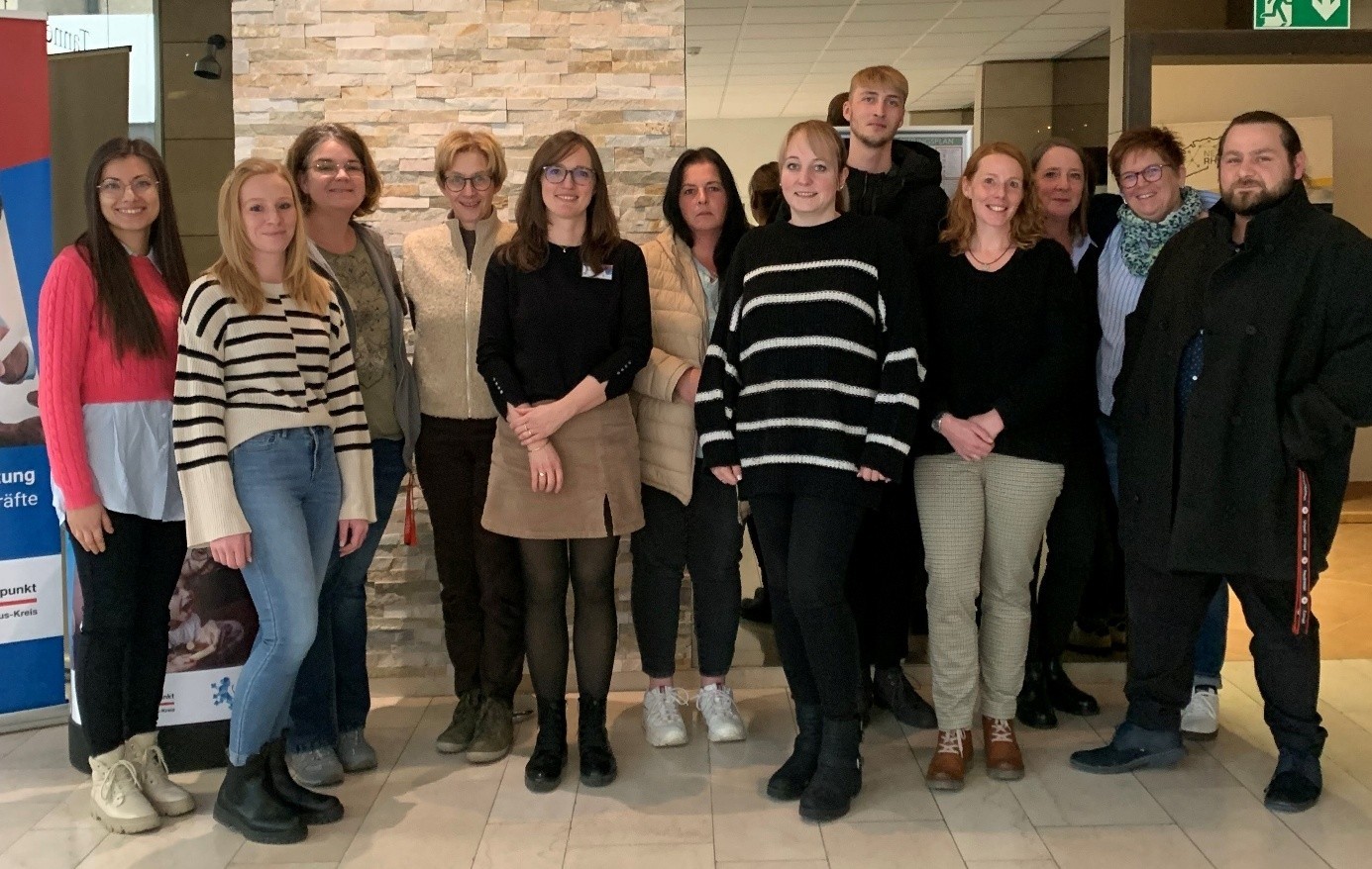 In einem Flur stehen 10 Frauen und 2 Männer für ein Gruppenfoto.