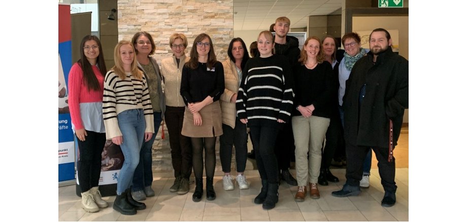 In einem Flur stehen 10 Frauen und 2 Männer für ein Gruppenfoto.