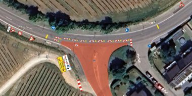 Luftbild einer Straße mit Wohngebäuden und Weinbergen sowie Markierungen einer Straßensperre in rot.