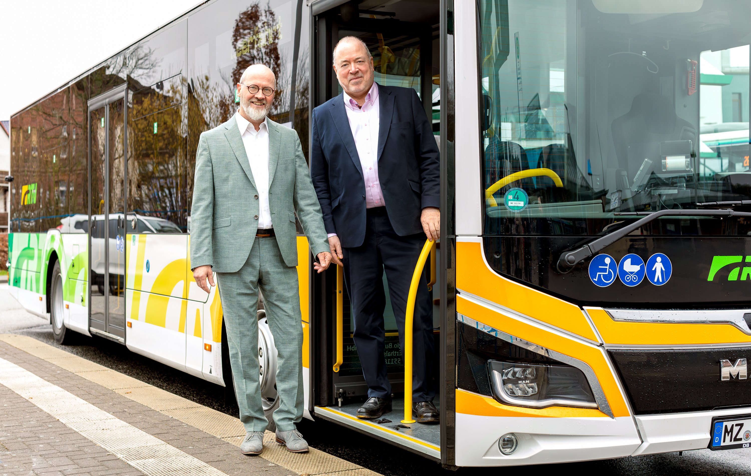 Personennahverkehrbus mit grüner und gelber Folie und weißen Buchstaben RTV mit Andreas Remler, Geschäftsführer der RTV und Arno Brandscheid, Vorsitzender der Geschäftsführung der RTV.