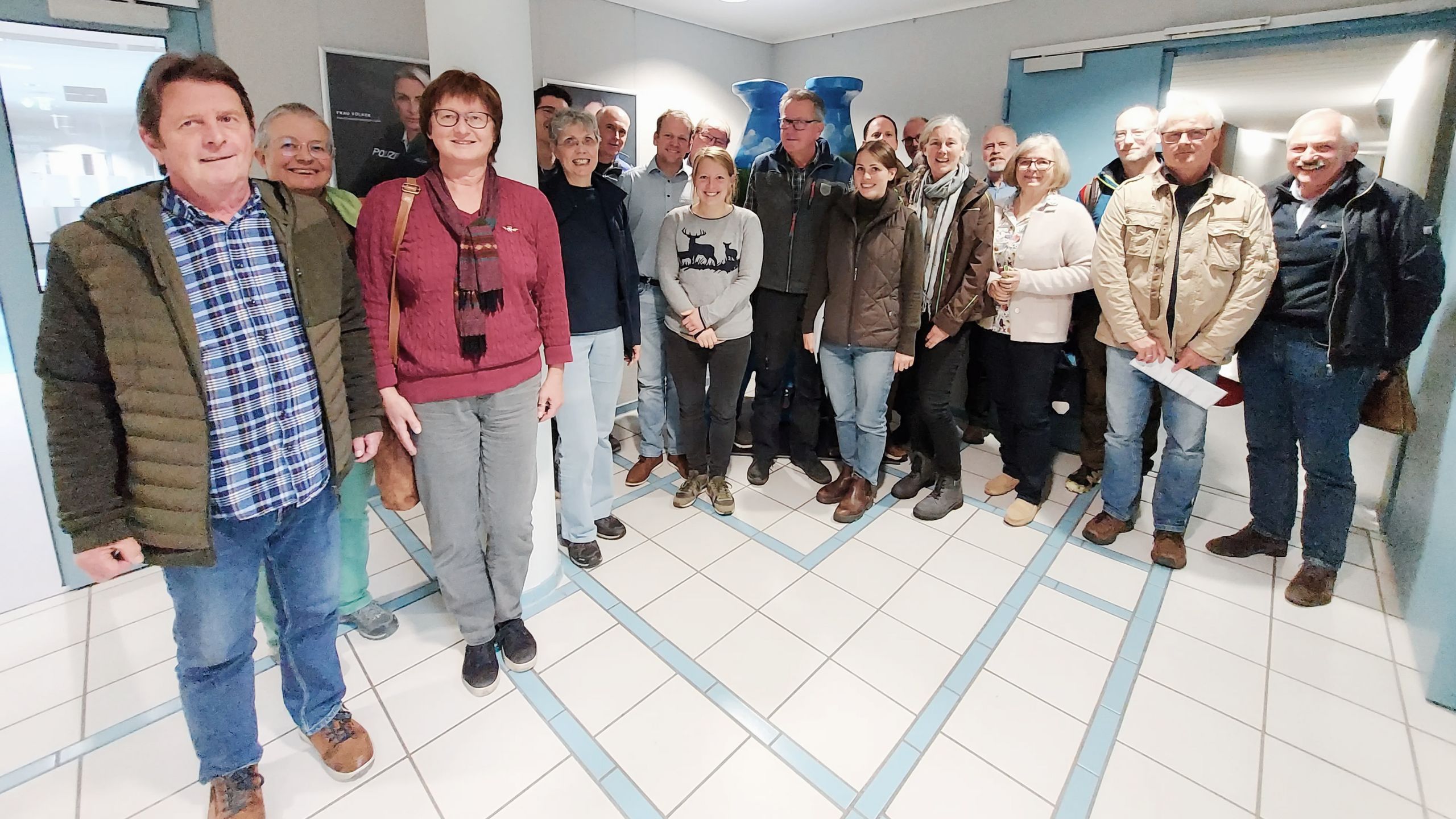 19 Personen stehen im Halbkreis zusammen.