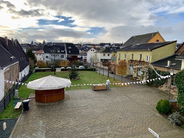 Blick auf den Josef-Staab-Platz mit aufgebautem Glühweinstand und geschmücktem Tannenbaum und einer weißen Wimpelkette auf der Bilder gemalt sind.