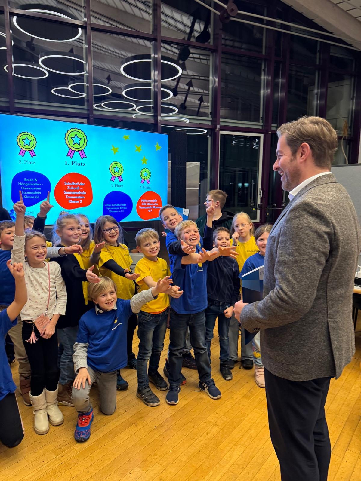 Landrat Sandro Zehner steht vor Schülern der 3. Klasse der Sonnenschule Taunusstein-Neuhof.