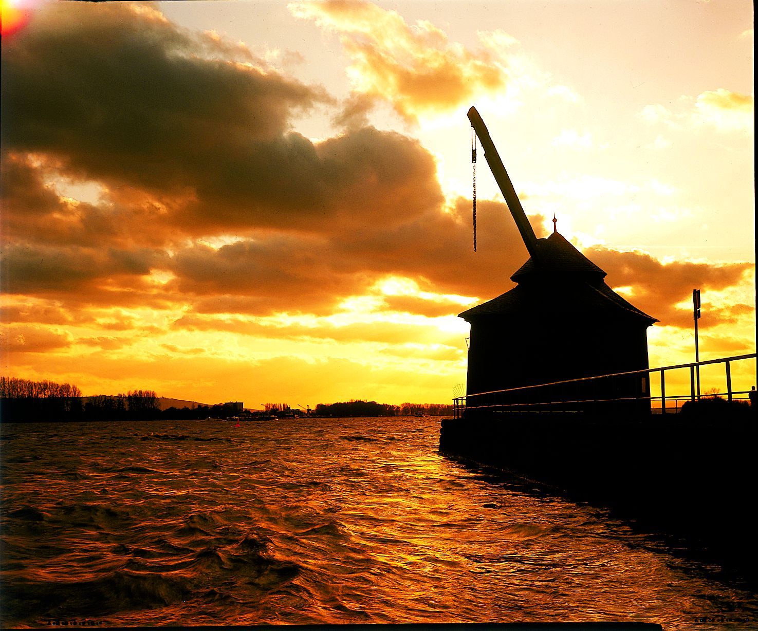 Ladekran in Abenddämmerung mit Wolken am Fluss Rhein.