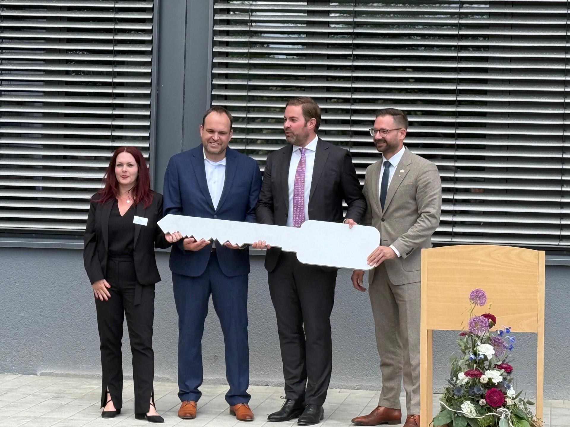 Landrat, Schulleiter, Bürgermeister und Abteilungsleiterin halten einen großen Schlüssel in der Hand, im Hintergrund ist die Schule