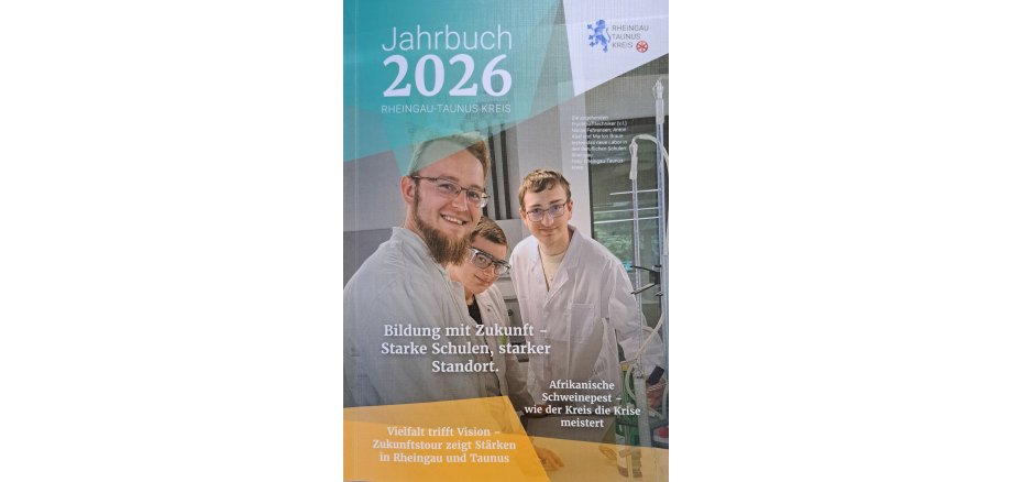 Titelblatt des Jahrbuches 2026 des Rheingau-Taunus-Kreises auf dem drei junge Männer in weißen Kitteln mit kurzen blonden Haaren mit zwei normalen Brillen und einer Schutzbrille in einem Labor stehen. Ein Mann trägt Bart.