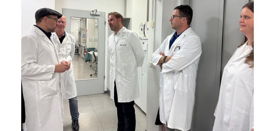 Newsfeed Bild - 260629_SGS Institut Fresenius Vier Männer und eine Frau stehen zusammen. Sie tragen weiße Kittel.