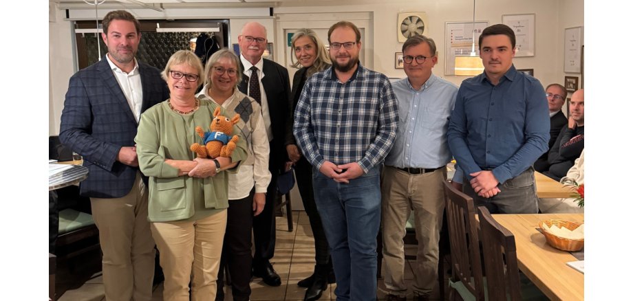 (v.l.n.r.): Landrat Sandro Zehner, Patricia Garnadt, Carola Hehner, Thomas Zadar (Dezernent LWV, Demografie und Teilhabe), Maren Görg, Christoph Müller, Stefan Münzer, Tim Engelhardt Fünf Männer und drei Frauen stehen nebeneinader. Eine Frau hält einen gehökelten Hasen auf dem Arm. Rechts sitzen zwei Herren an einem Tosch.