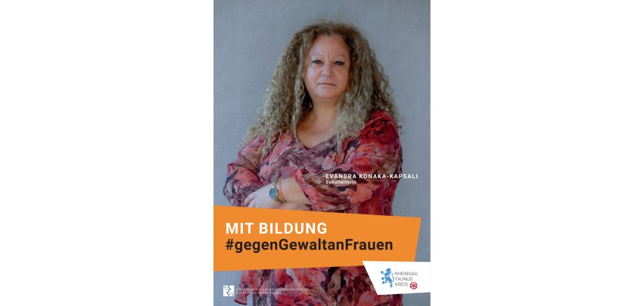 Vor einem grauen Hintergrund steht eine Frau in rosa-rot-weinrot-geblümter Bluse. Sie verschränkt die Arme vor ihren Körper und trägt eine rosefarbene Uhr mit schwarzem Ziffernblatt sowie ein rosa Spiralhaarband. Die blonden Haare sind gelockt und lang. Der Blick ist ernst.