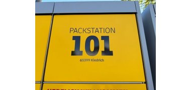 Man sieht ein gelbes Fach einer Packstation mit der Packstationsnummer 101 und der PLZ sowie dem Ort.