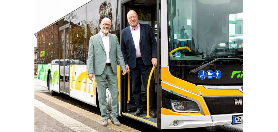 Personennahverkehrbus mit grüner und gelber Folie und weißen Buchstaben RTV mit Andreas Remler, Geschäftsführer der RTV und Arno Brandscheid, Vorsitzender der Geschäftsführung der RTV