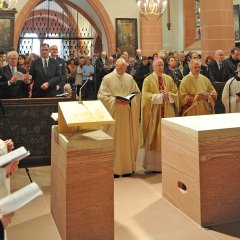 Blick vom Altar aus in den voll besetzten Kirchenraum mit in den Bänken stehenden Kirchenbesuchern. Um den Altar stehen Pfarrer, ein Diakon und Sänger der Kiedricher Chorbuben.