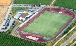 Luftbild der Winfried-Steinmacher-Sportanlage mit Fussballfeld, Laufbahn, Vereinsheim, Parkplätzen und Weinbergen 